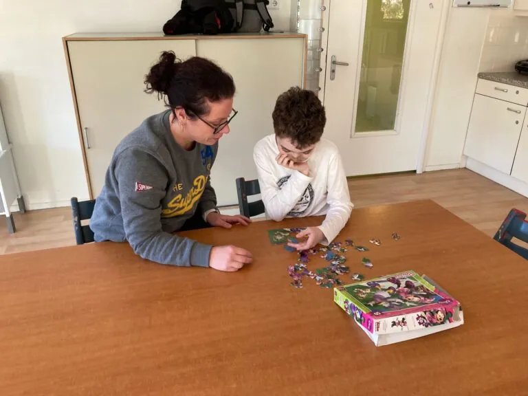 Medewerker is met een cliënt een puzzel aan het maken